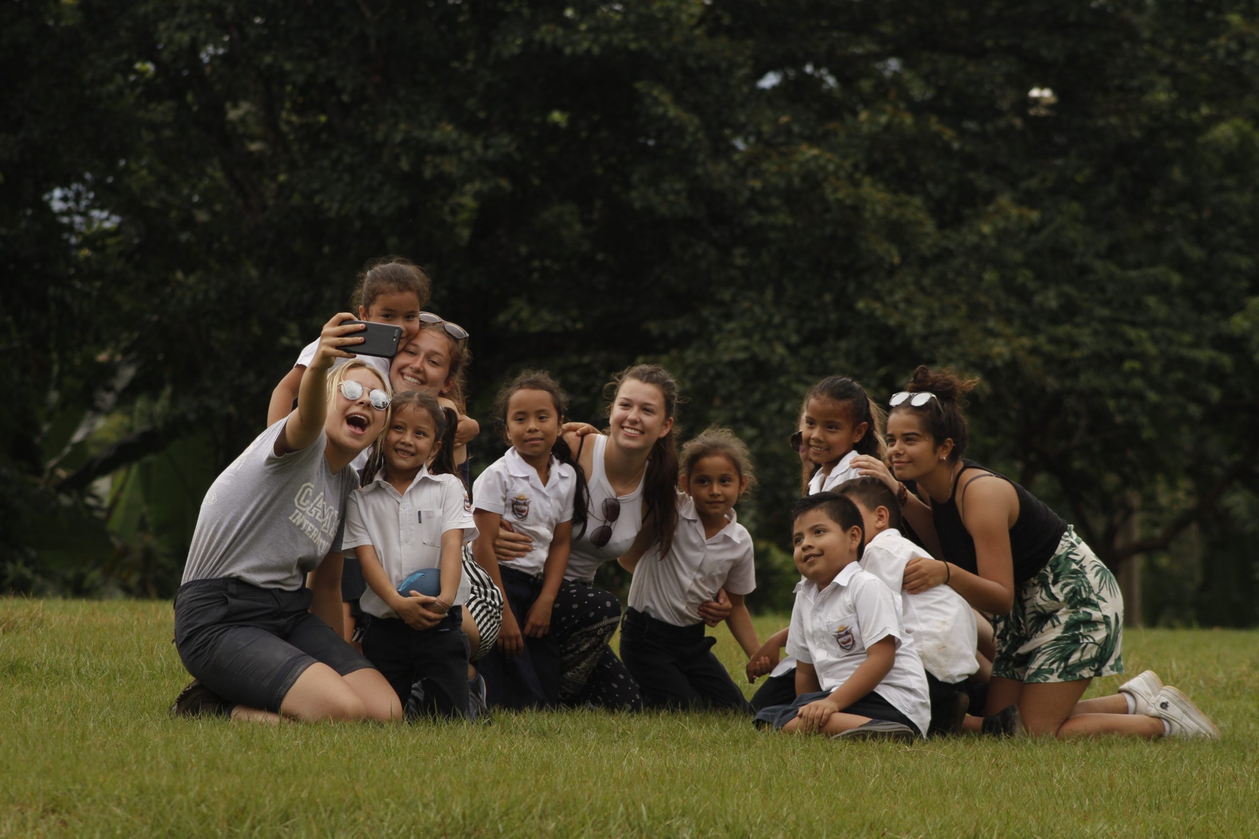 Group of travellers and local children taking photos together in Costa Rica