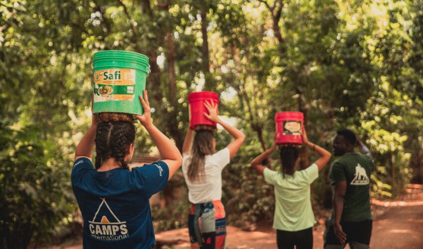 student travellers walking with water buckets on their heads in Tanzania