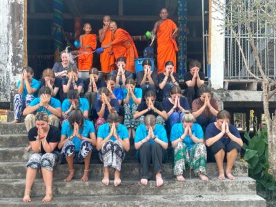 Travellers being blessed with water by Monks at temple in Cambodia.