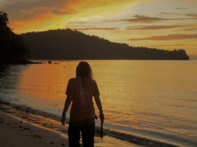 Traveller looking over ocean at sunset.