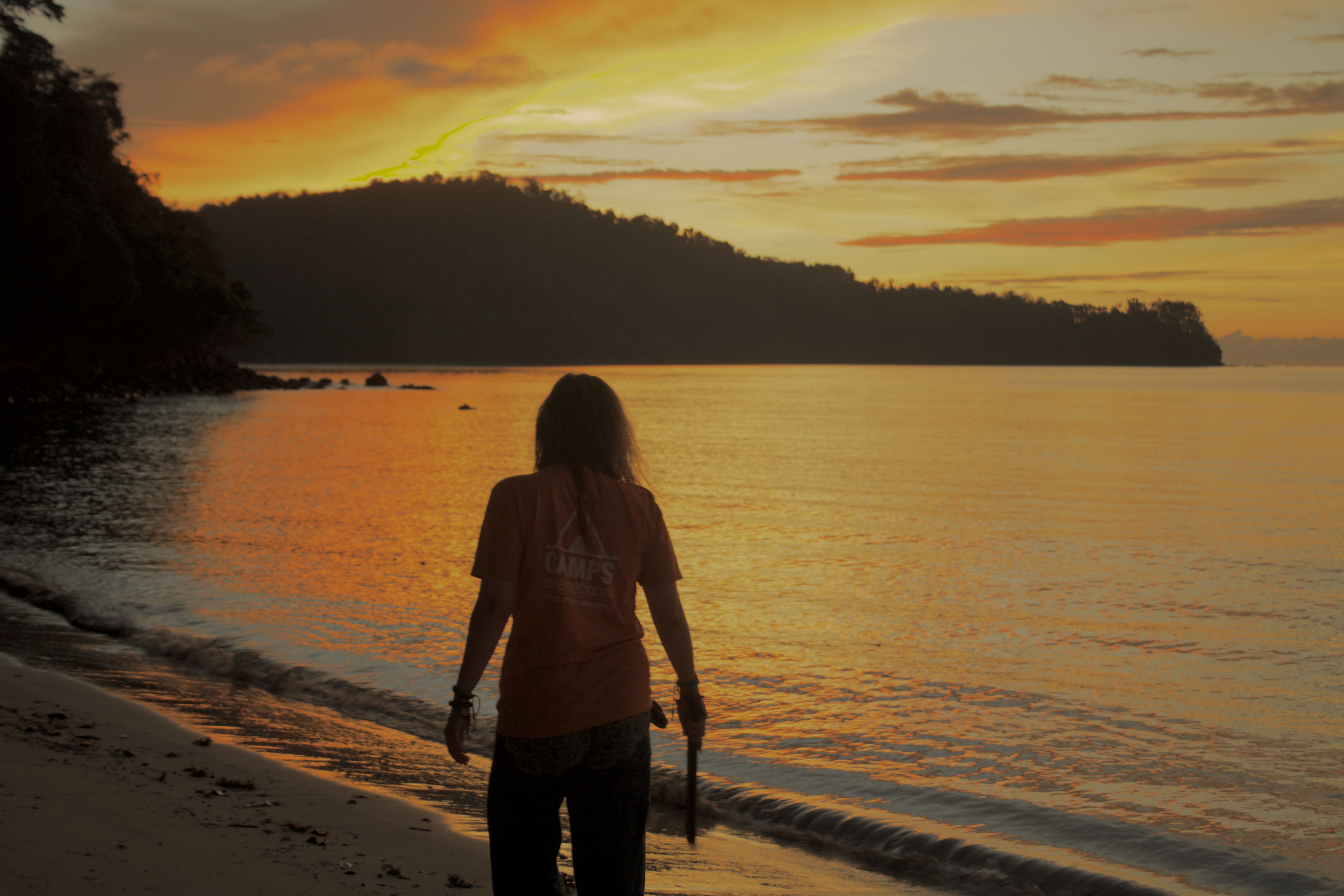 Traveller looking over ocean at sunset.