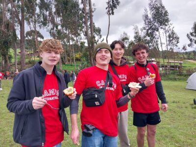 Young adults with red Camp Peru t-shirts trying granadilla on a camps international expedition