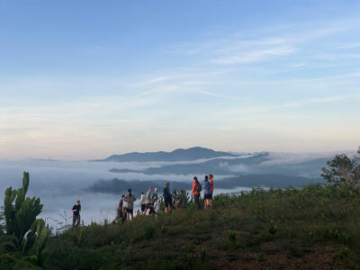 group of travellers standing on top of a hill enjoying the sunset in borneo