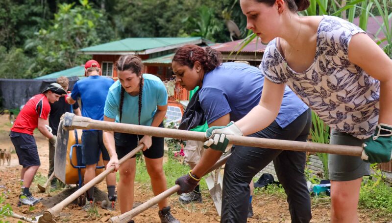 Travellers digging a road in a project in Borneo