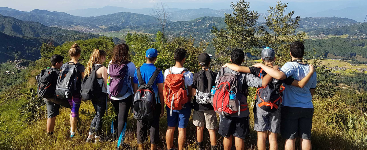 Group of students all standing facing away from the camera with their arms around each others shoulders, looking out at an incredible view on the Nepal Silver International Award trek with Camps International.