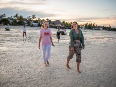 Two girls walking on the beach at sunset