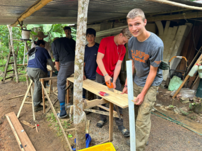 Group of students doing woodwork under a canopy