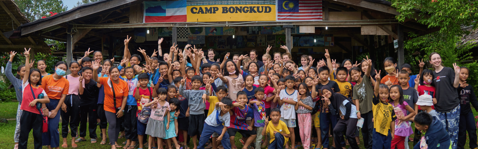 Group of travellers and locals posing together in front of the camp in Borneo