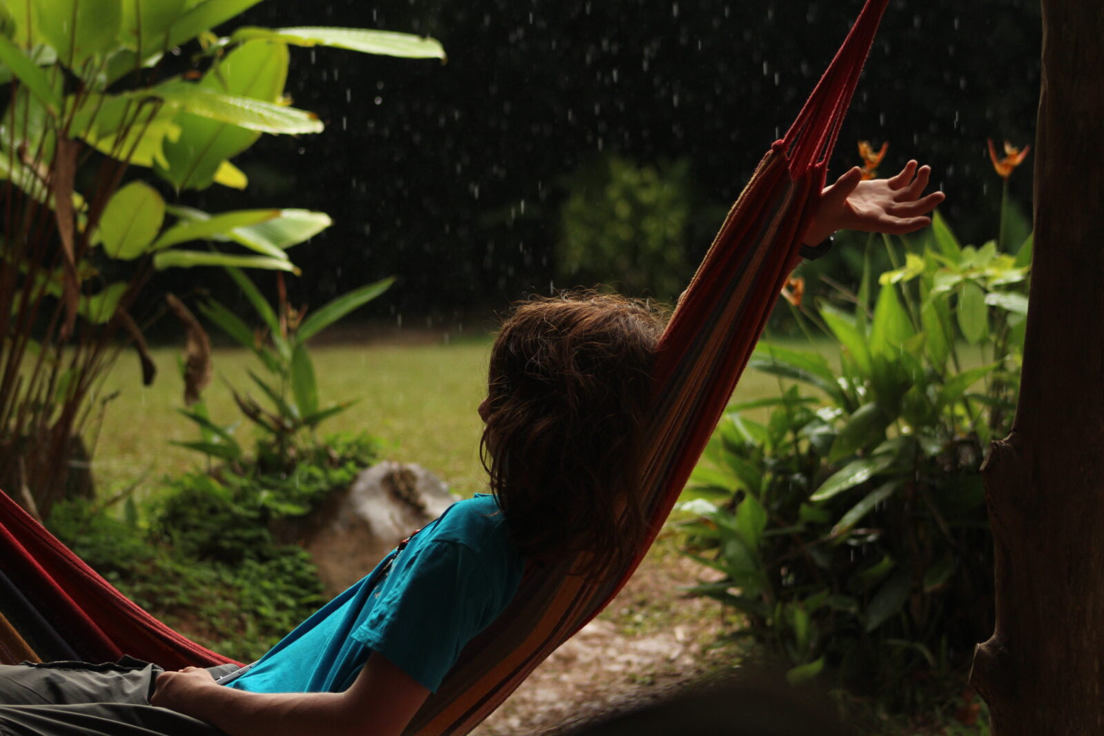 A traveller laying in a hammock on a rainy day in Costa Rica with lots of greenery around them