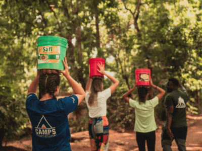 student travellers wearing buckets with water on their heads in Tanzania