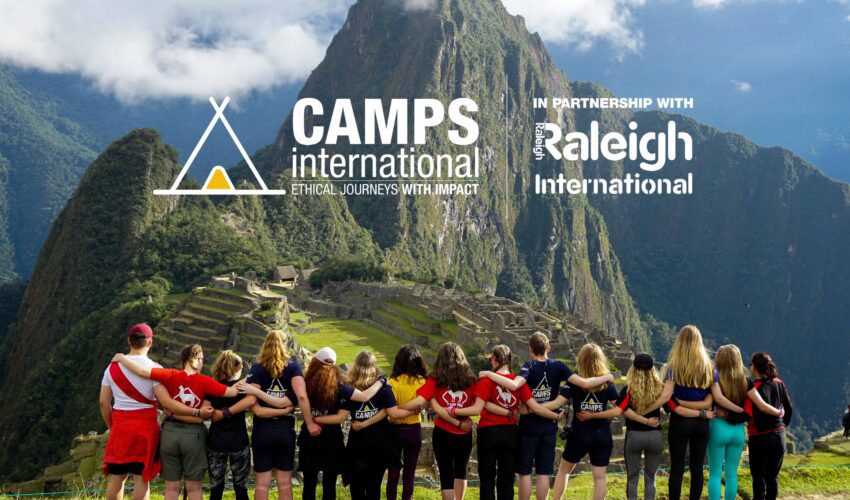 a group of students travellers standing next to each other in front of Machu Picchu in Peru