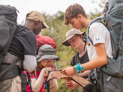 group of student travellers with backpacks looking at a map