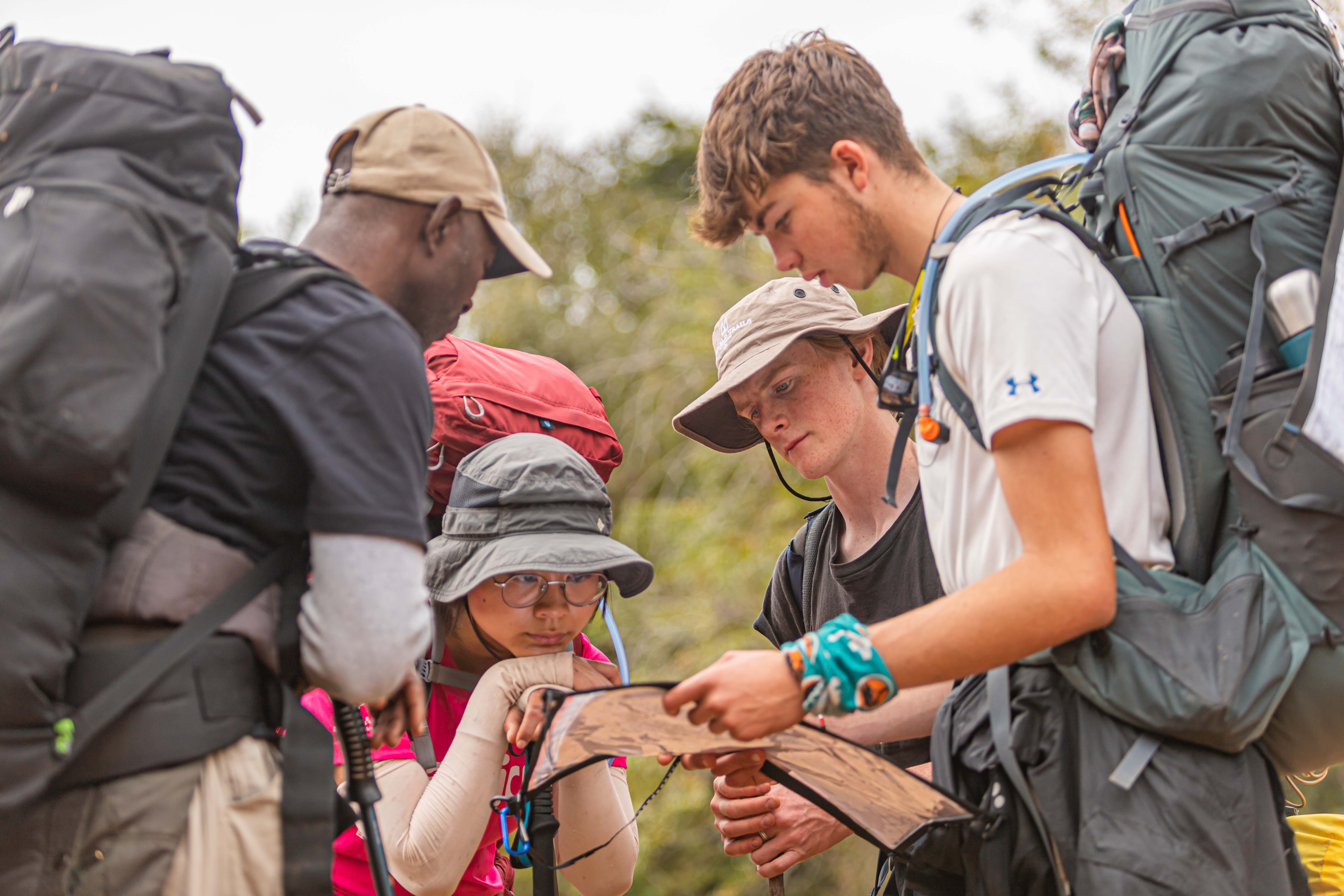 group of student travellers with backpacks looking at a map