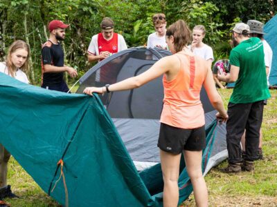 group of student travellers putting up a tent together