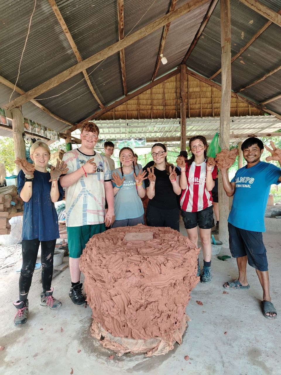 group of student travellers standing around a clay water pot they have been making