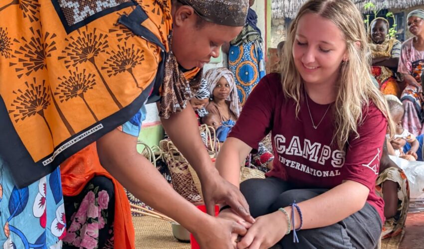 girl traveller and a local woman in Kenya making chapatis together