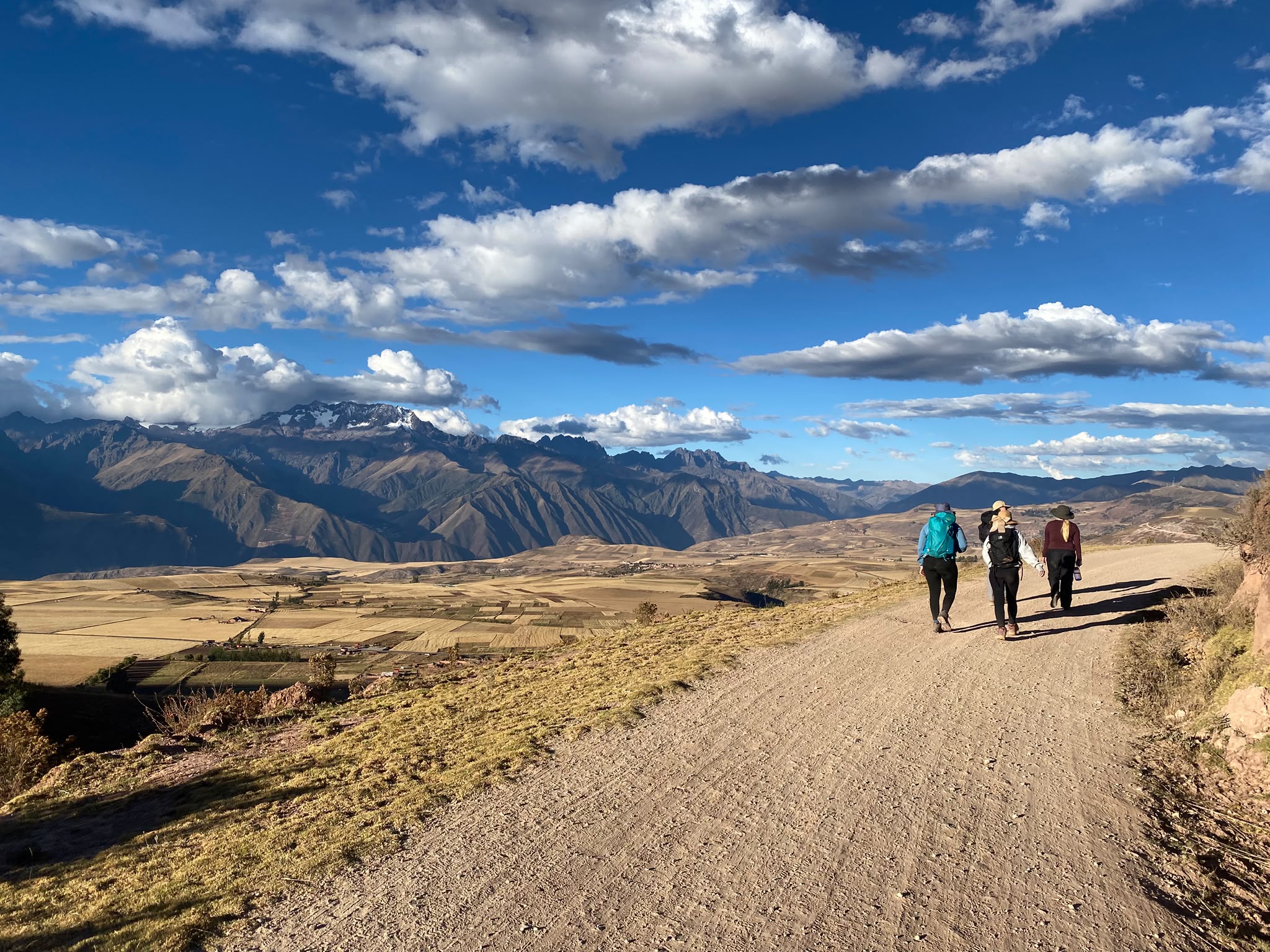 three student travellers walking in Peru with view of the mountains in the distance