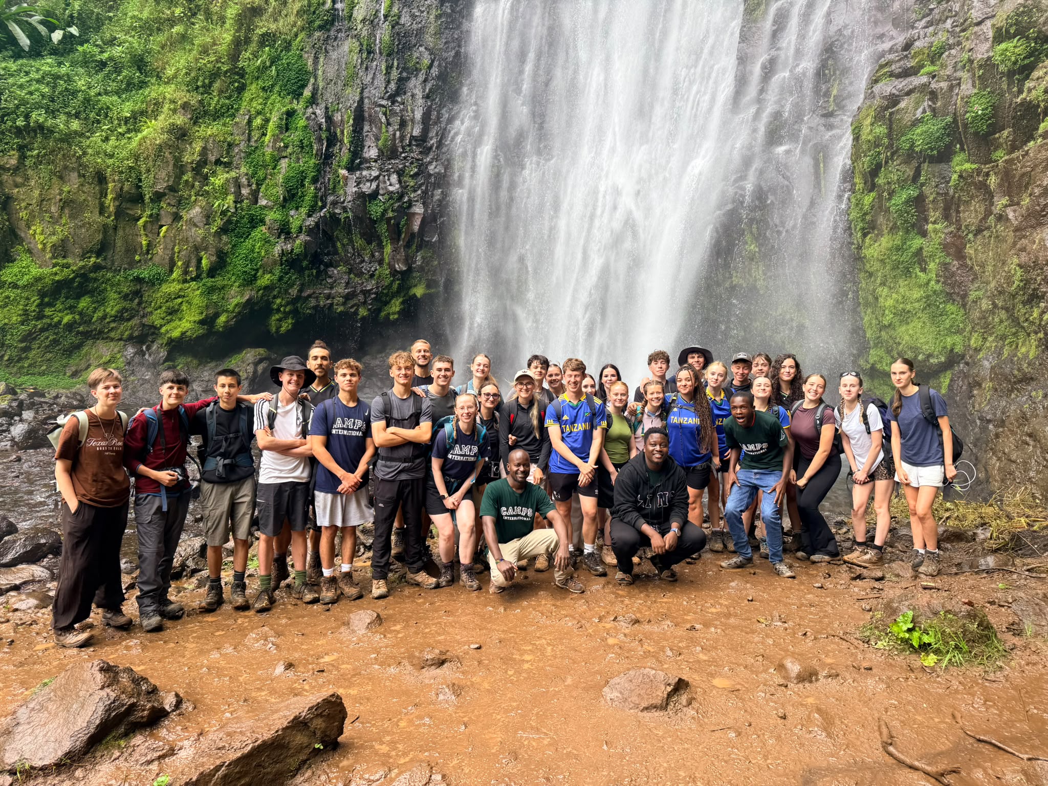 a group of travellers standing in front of waterfall Materuni in Tanzania